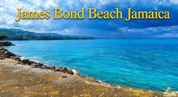 James Bond Beach Jamaica with turquoise Caribbean waters, rocky shore, lush hills, and a bright blue cloudy sky.