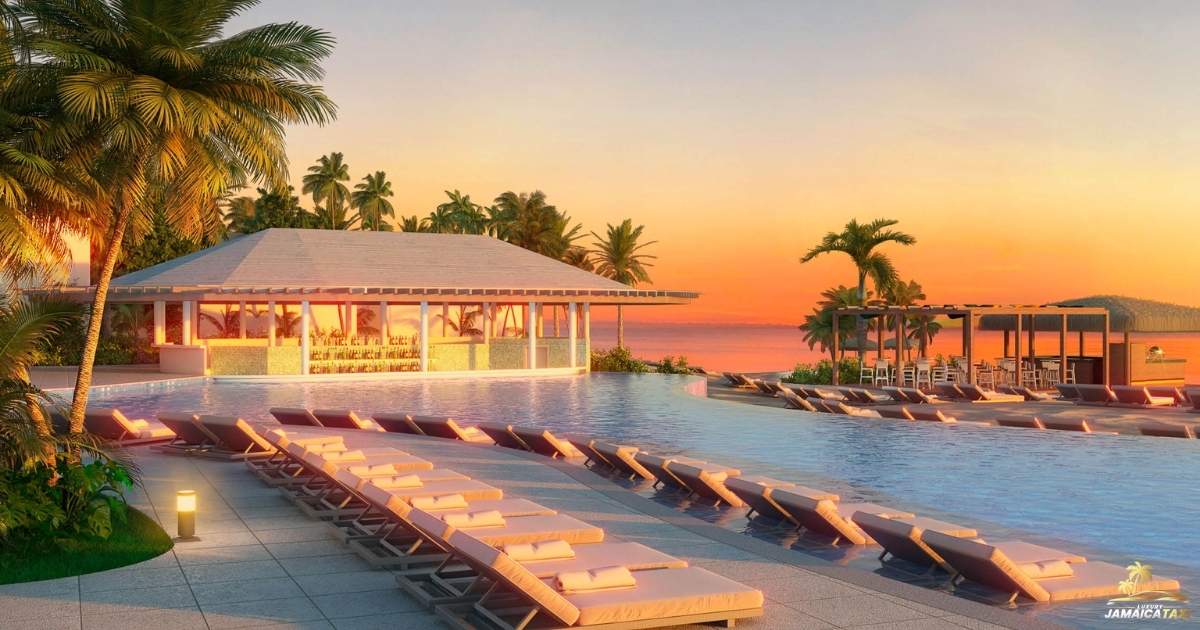 Pool area with lounge chairs and a building at sunset, surrounded by palm trees.