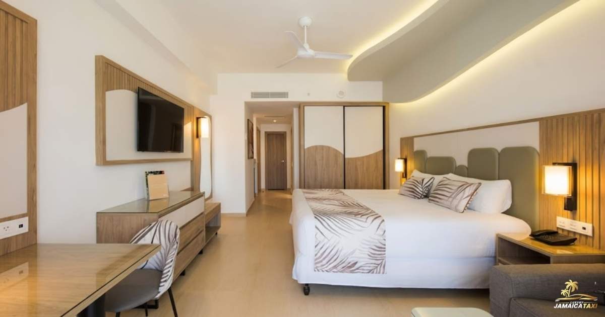Modern hotel room with bed, desk, and television.
