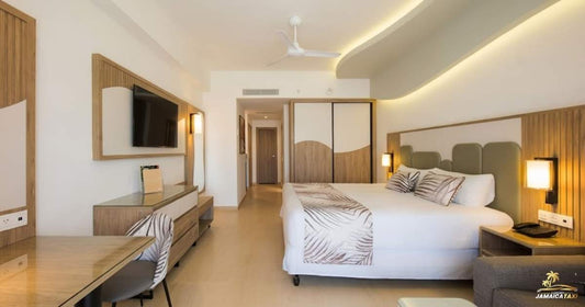 Modern hotel room with bed, desk, and television.